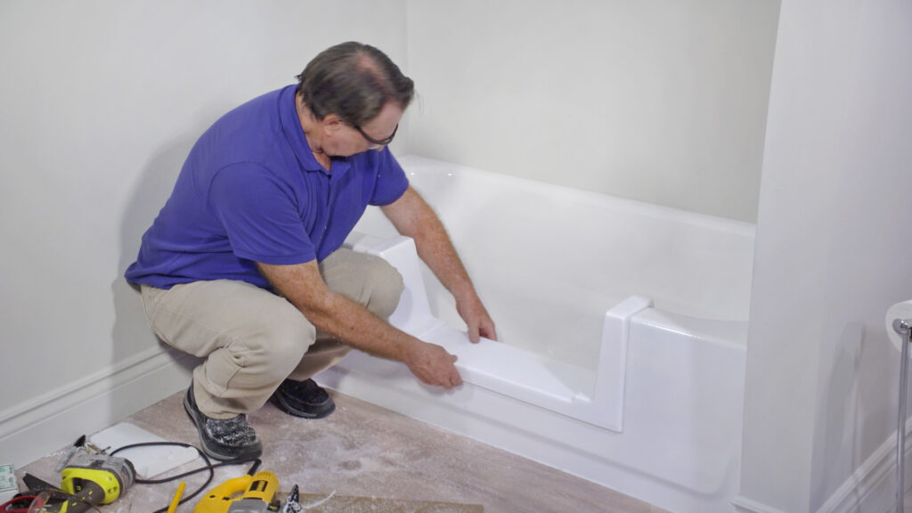 Installer fitting a tub access conversion